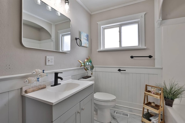 bathroom with a wainscoted wall, plenty of natural light, toilet, and vanity