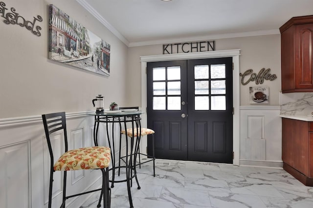 foyer entrance featuring a wainscoted wall, marble finish floor, french doors, and crown molding