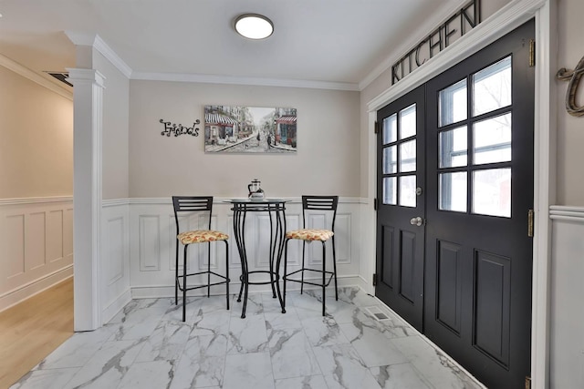 dining space featuring wainscoting, marble finish floor, and crown molding