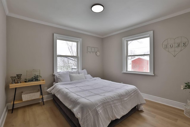 bedroom with light wood finished floors, crown molding, and baseboards