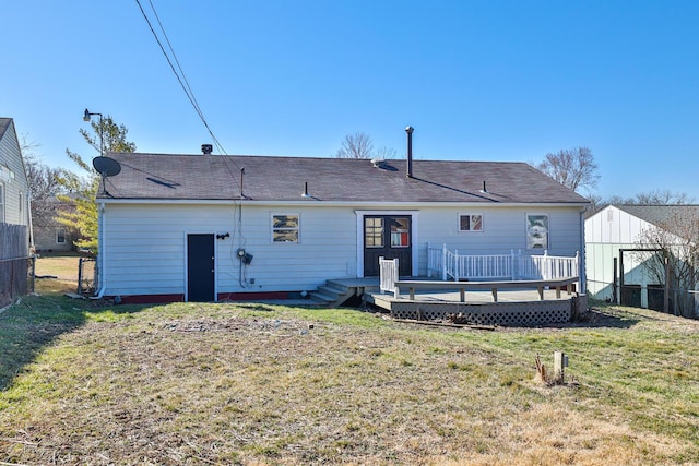 back of property with a wooden deck, a yard, and fence