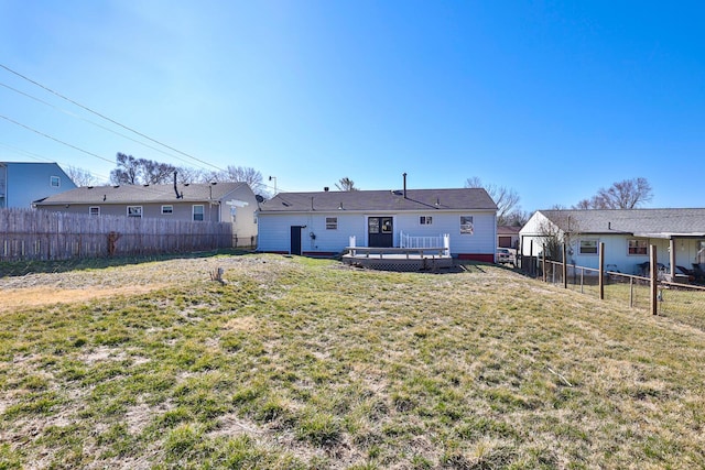 rear view of house with a wooden deck, a lawn, and a fenced backyard