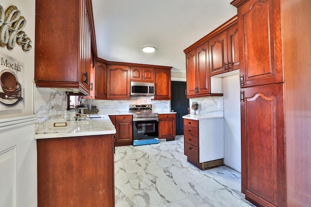 kitchen featuring decorative backsplash, light countertops, marble finish floor, and appliances with stainless steel finishes