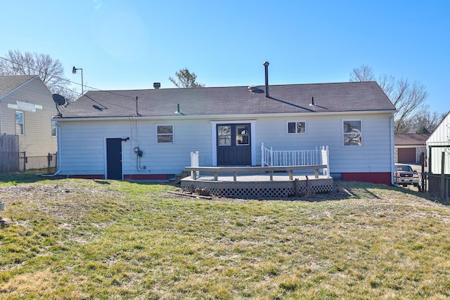 rear view of house with a lawn, a deck, and fence