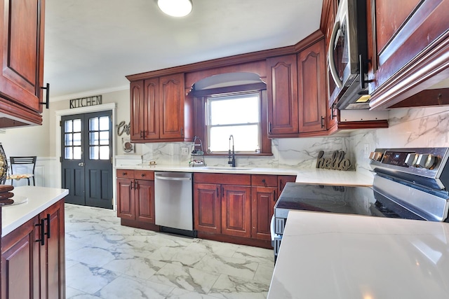 kitchen featuring marble finish floor, a sink, appliances with stainless steel finishes, crown molding, and light countertops