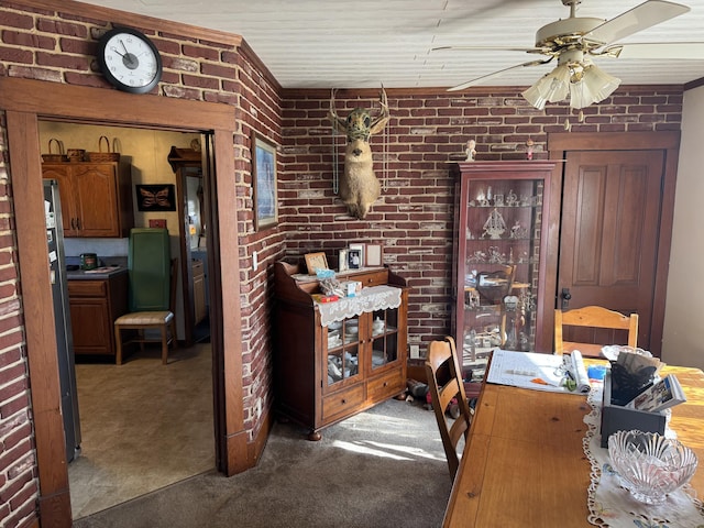 carpeted dining room featuring brick wall and ceiling fan