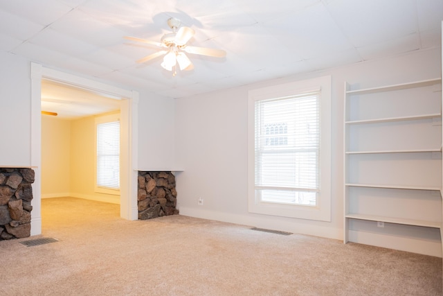 unfurnished living room with ceiling fan, light colored carpet, and a fireplace