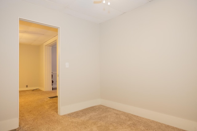 carpeted spare room featuring a drop ceiling and ceiling fan