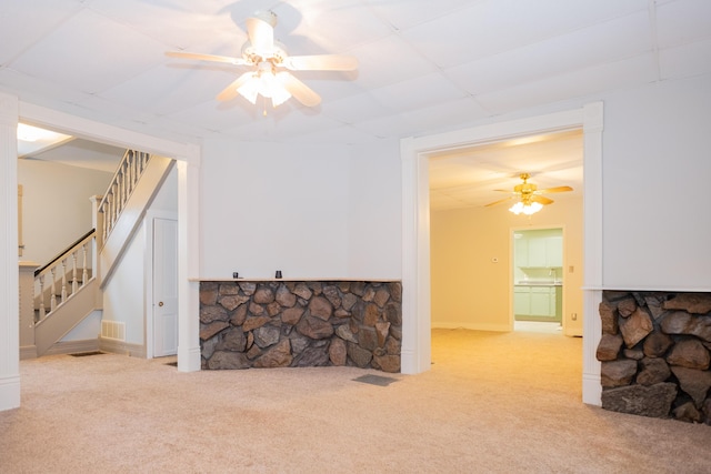 carpeted living room with ceiling fan and a fireplace