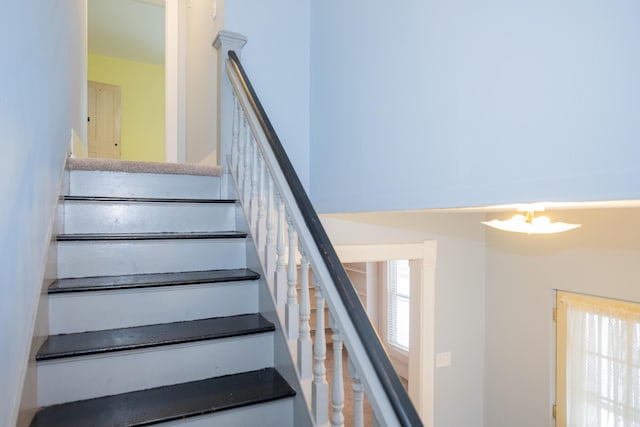 stairway with a wealth of natural light and a chandelier