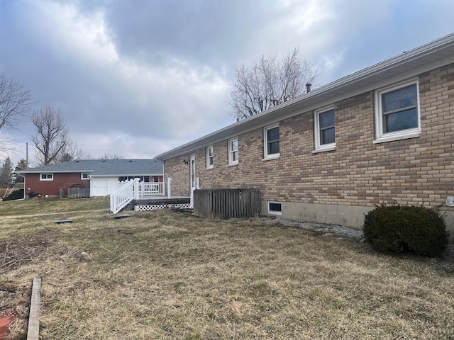 back of property featuring brick siding, a lawn, and a wooden deck