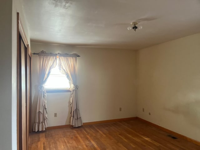 empty room with baseboards, visible vents, and wood finished floors