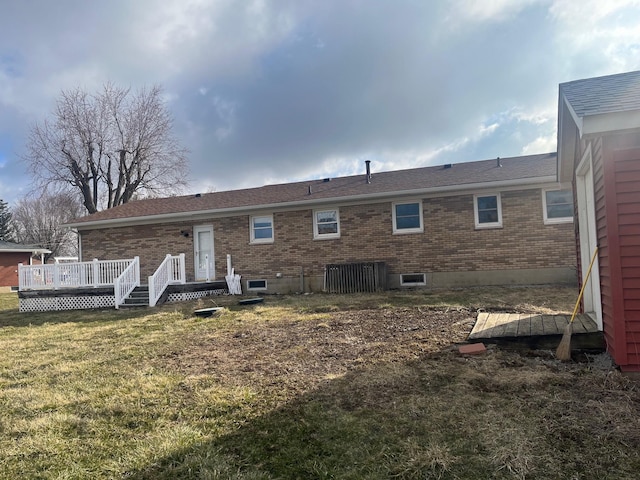 back of house with brick siding, a yard, and a deck