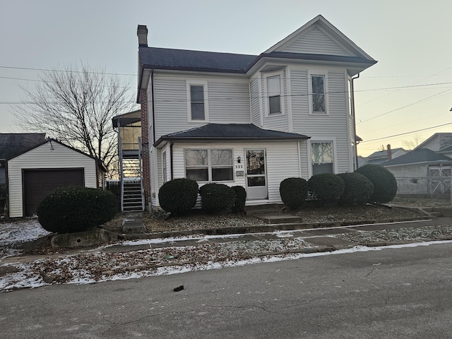 view of front of property featuring a detached garage, an outbuilding, and a chimney