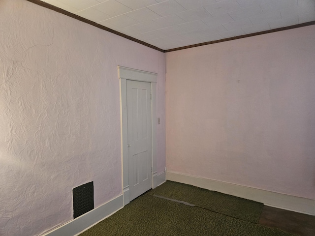 unfurnished room featuring crown molding, baseboards, and dark carpet