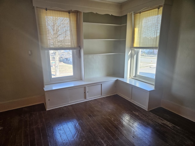 spare room with baseboards and dark wood-style flooring