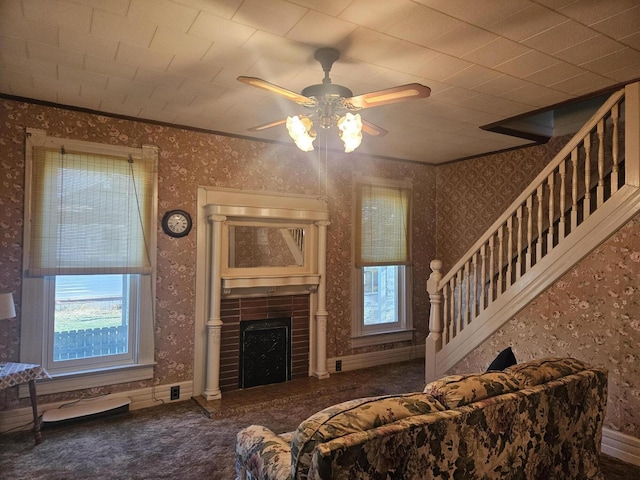 carpeted living area with a healthy amount of sunlight, a fireplace, wallpapered walls, and ornamental molding