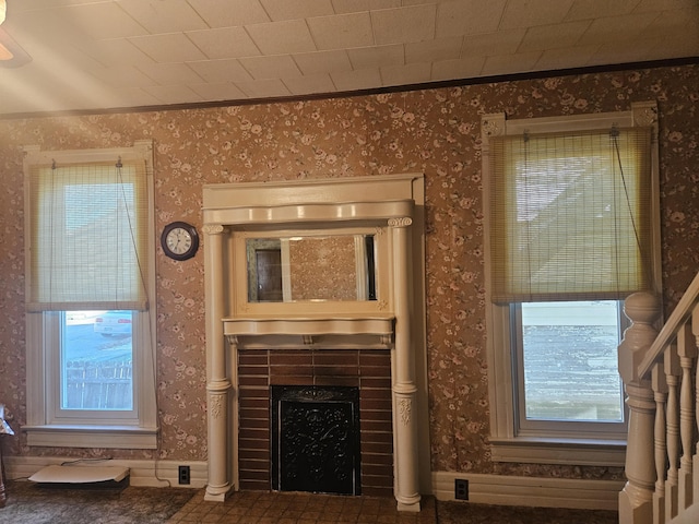 living area with a tile fireplace, wallpapered walls, and ornamental molding