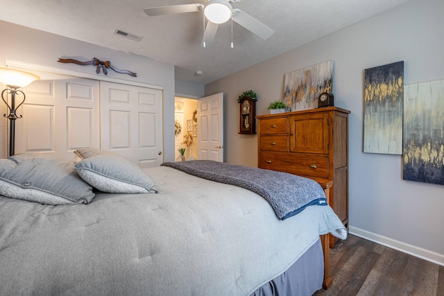 bedroom with visible vents, baseboards, dark wood finished floors, a closet, and a textured ceiling