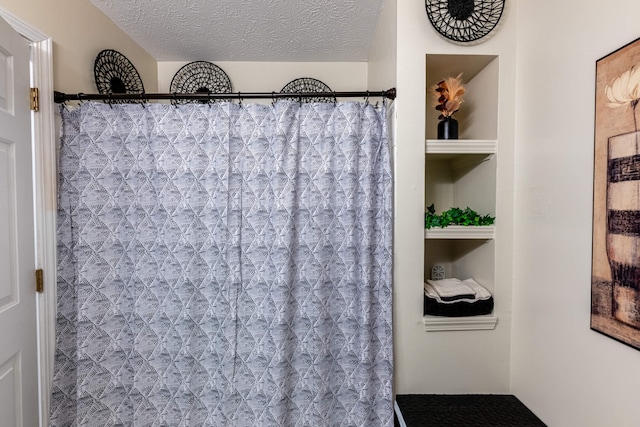 bathroom featuring curtained shower, built in shelves, and a textured ceiling