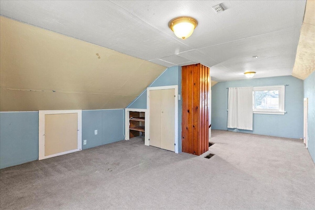 additional living space featuring vaulted ceiling and light colored carpet