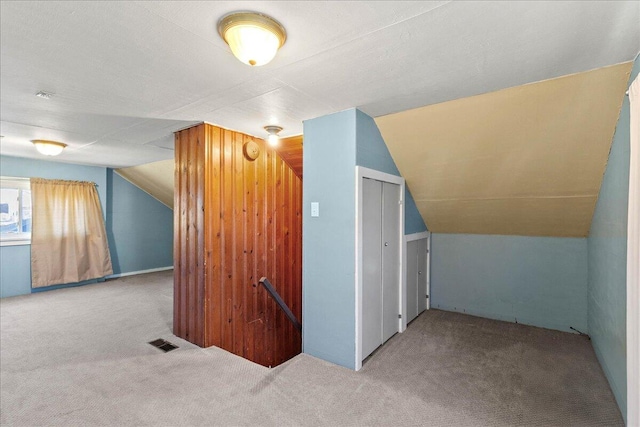 additional living space featuring vaulted ceiling and light colored carpet