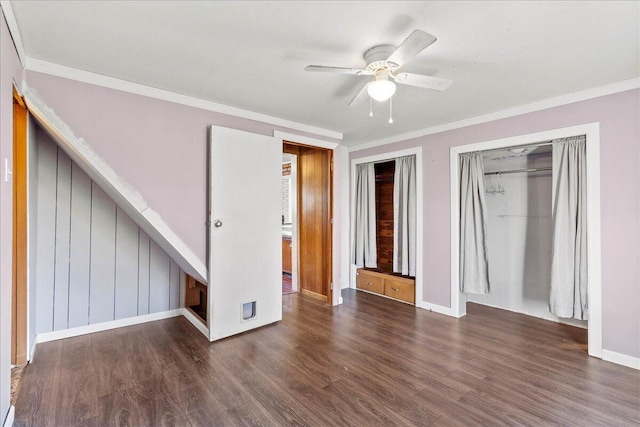 unfurnished bedroom featuring multiple closets, ornamental molding, dark wood-type flooring, and ceiling fan