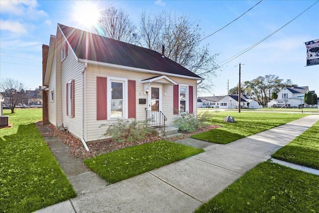 bungalow-style house featuring cooling unit and a front lawn