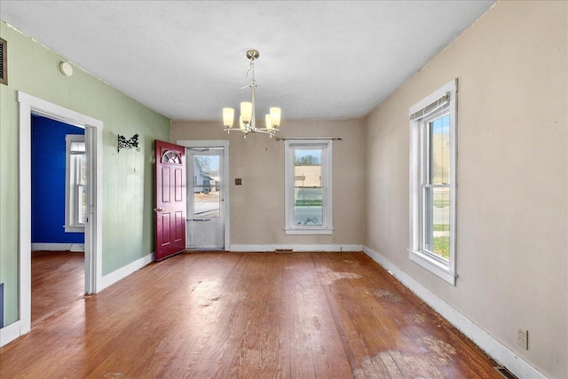 unfurnished dining area featuring hardwood / wood-style floors, a notable chandelier, and plenty of natural light