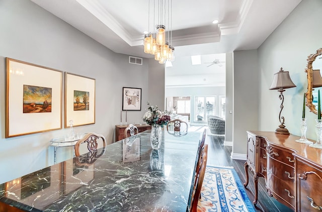 dining area featuring ornamental molding, dark hardwood / wood-style flooring, and a raised ceiling