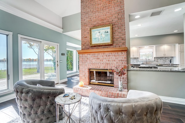 living room with a water view, dark hardwood / wood-style floors, and a brick fireplace