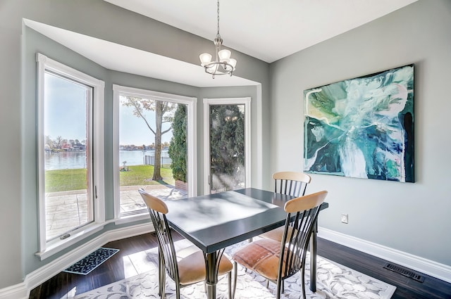 dining space featuring hardwood / wood-style floors, a notable chandelier, and a water view