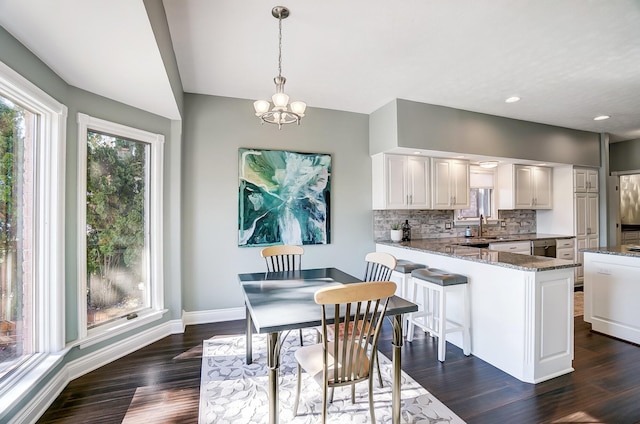 kitchen with white cabinetry, tasteful backsplash, hanging light fixtures, kitchen peninsula, and dark stone counters