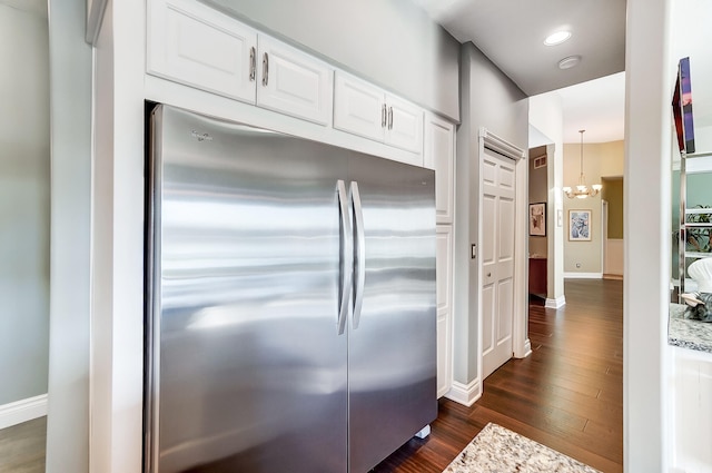 kitchen featuring white cabinetry, decorative light fixtures, stainless steel refrigerator, dark hardwood / wood-style flooring, and a notable chandelier