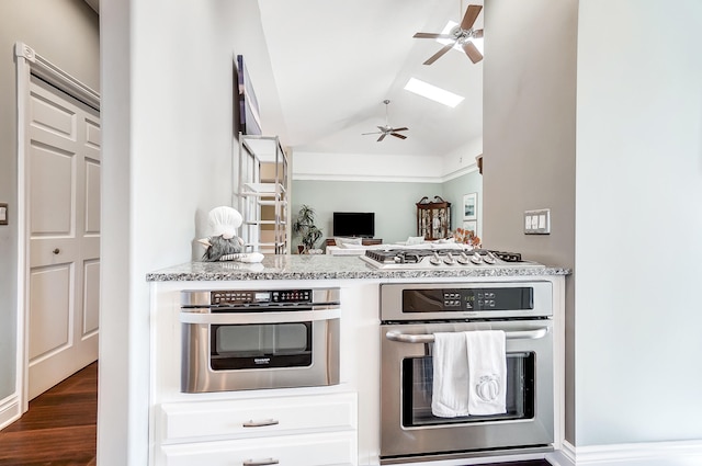 kitchen featuring lofted ceiling, light stone counters, dark hardwood / wood-style flooring, ceiling fan, and stainless steel appliances