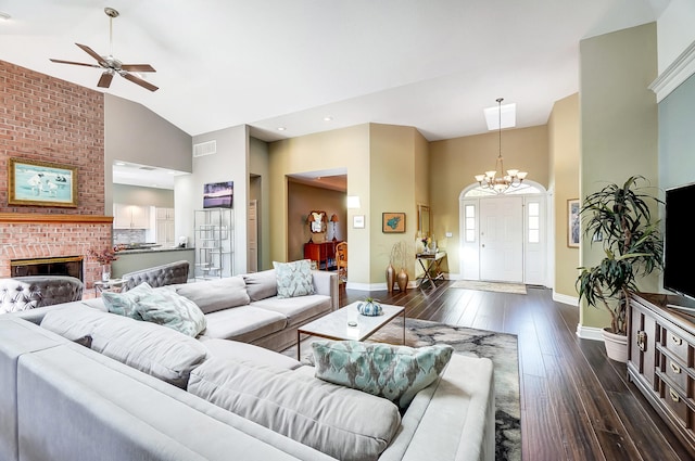 living room with a brick fireplace, ceiling fan with notable chandelier, dark wood-type flooring, and high vaulted ceiling