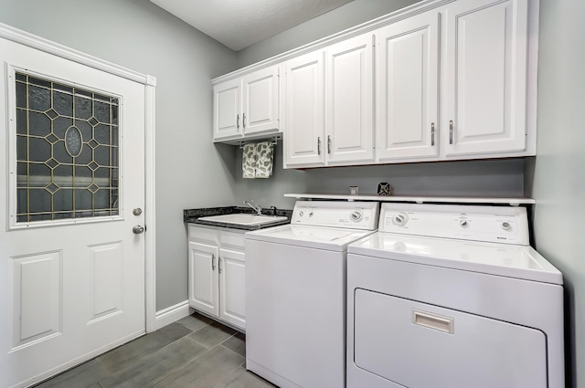 clothes washing area featuring cabinets, sink, and washer and clothes dryer