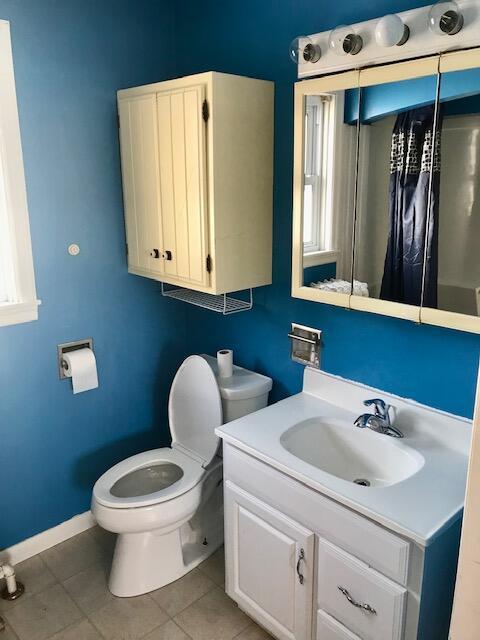 bathroom with toilet, tile patterned flooring, baseboards, and vanity