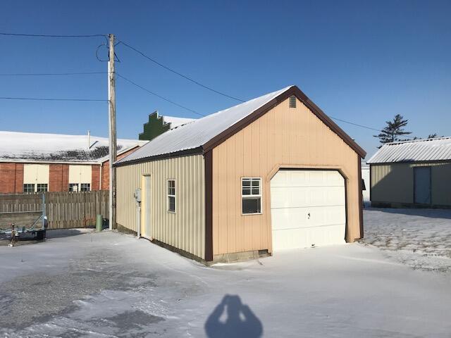 snow covered garage with a garage and fence