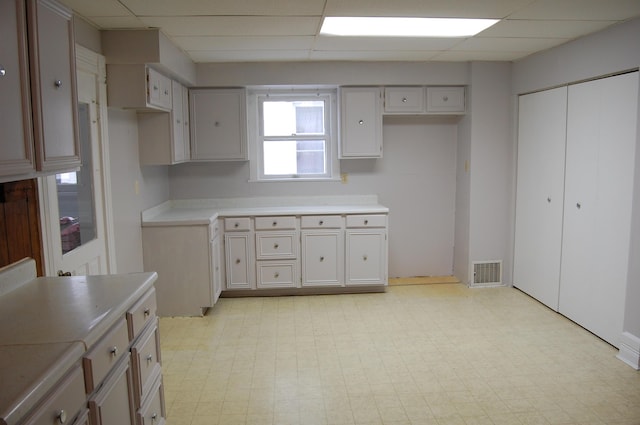 kitchen with a paneled ceiling, visible vents, and light floors