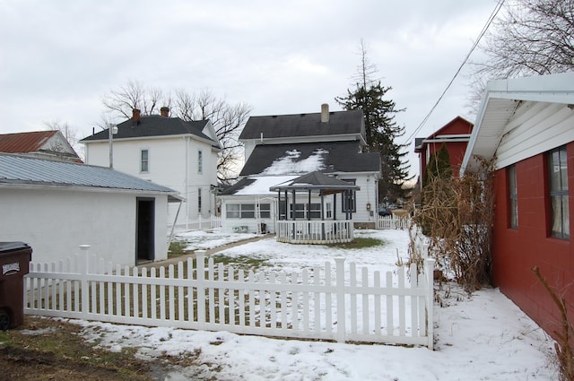 snow covered rear of property featuring fence