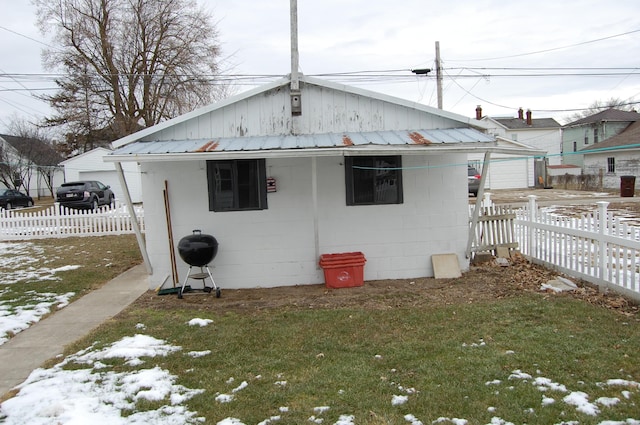 back of property with a yard, concrete block siding, fence, and metal roof