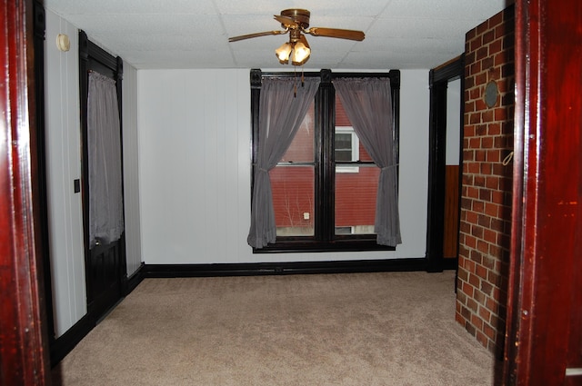 empty room featuring carpet, a drop ceiling, and ceiling fan