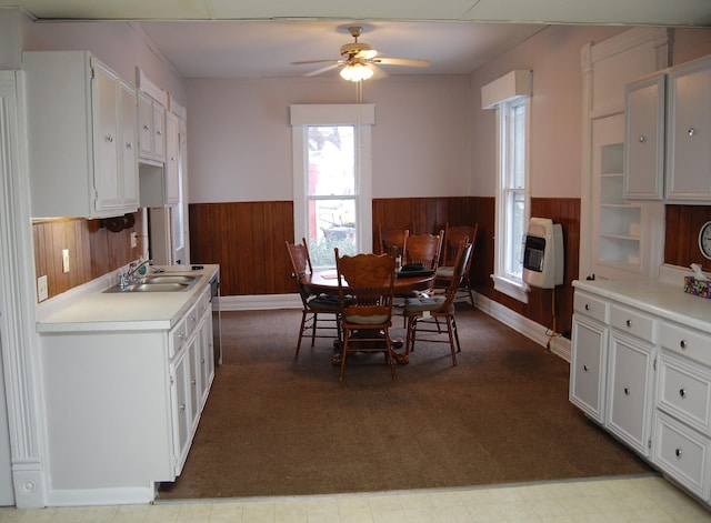 dining area with heating unit, wooden walls, a ceiling fan, wainscoting, and tile patterned floors