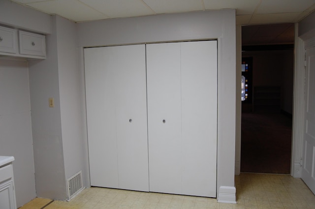 unfurnished bedroom with a closet, a drop ceiling, visible vents, and light floors