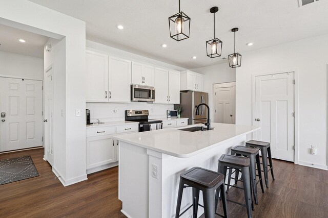 8202 Cherry Birch Dr, Tipp City, OH 45371 - kitchen with dark wood finished floors, a center island with sink, stainless steel appliances, white cabinets, and recessed lighting