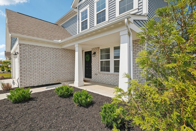 8202 Cherry Birch Dr, Tipp City, OH 45371 - doorway to property with a porch, brick siding, and roof with shingles