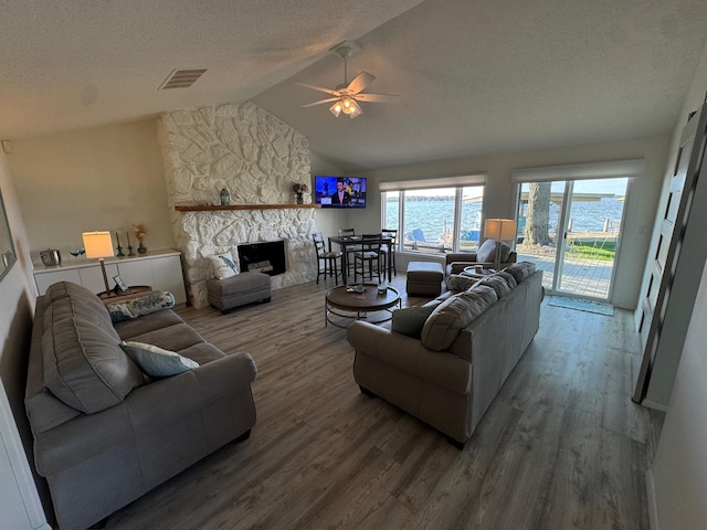 14072 Seminole Path, Lakeview, OH 43331 - living room featuring wood finished floors, ceiling fan, a stone fireplace, a textured ceiling, and lofted ceiling