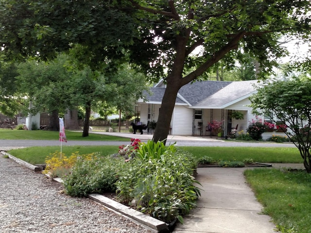 view of front of property with roof with shingles, covered porch, and a front yard