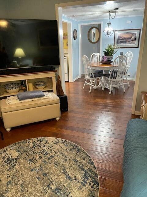 living area with wood-type flooring, ornamental molding, and baseboards
